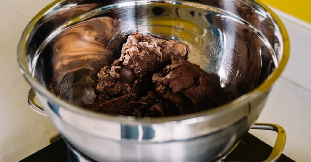 A stainless steel bowl with chocolate melting on an electric stove, ideal for culinary projects.